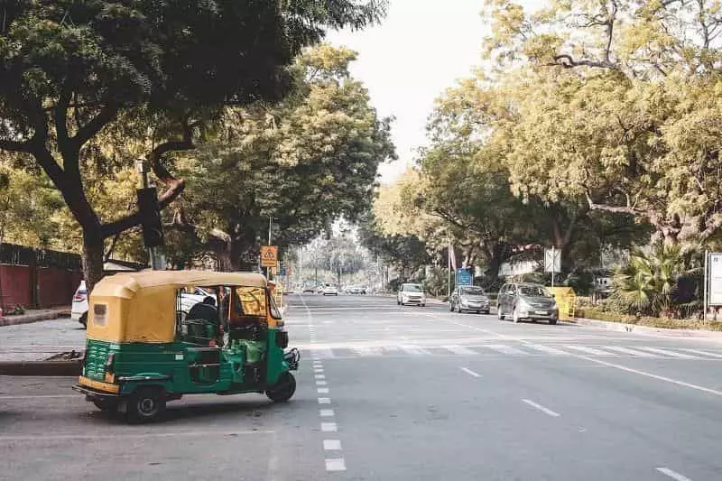 A rikshaw driver crossing road is shown in the image.