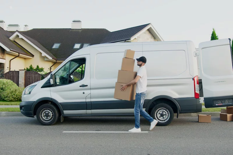 A man is carring boxes from the van.