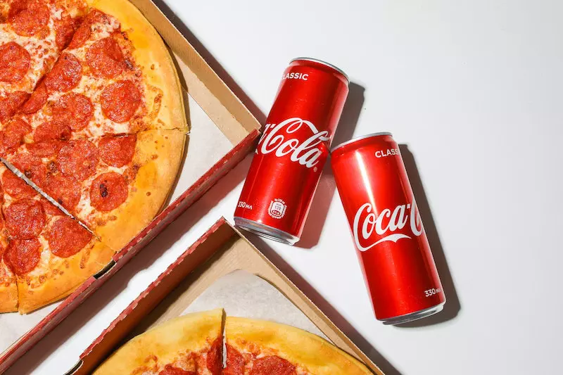 Cold drink and pizza is shown in the image