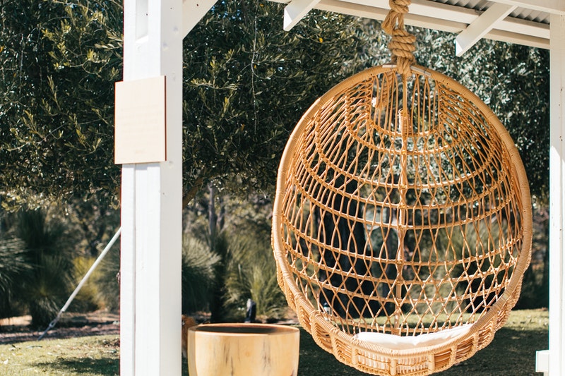 A Wooden Swing is Hanging by Rope on a Pillar