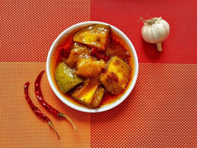 Garlic, Mirch and A Bowl Filled With Pickle Kept on Table