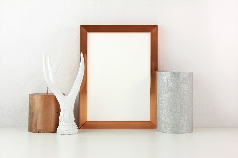 A Wooden Frame Between Two Candle and A Showpiece is Display on Table