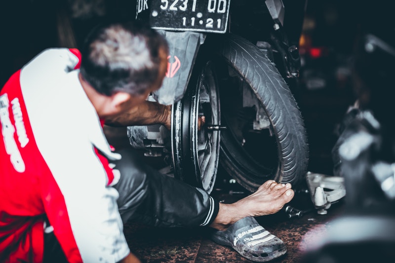 A Man Changing Tyre of Bike At Garage