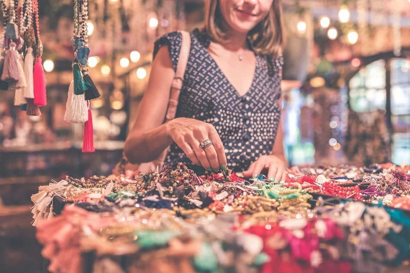 A Girl Wearing Blue Top and Hanging Purse on Shoulder Buying Accessories From Shop