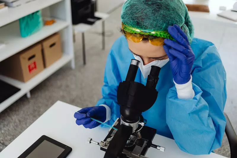 A lady is seing specimen from microscope