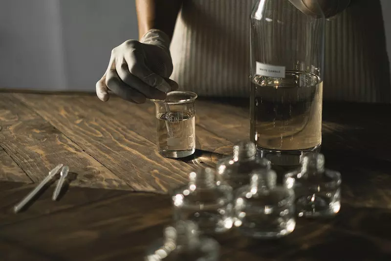 A woman preparing aromatic perfume while mixing fluid in glassware