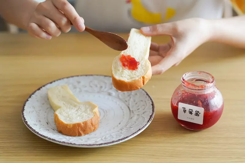 Someone is applying jam on the bread
