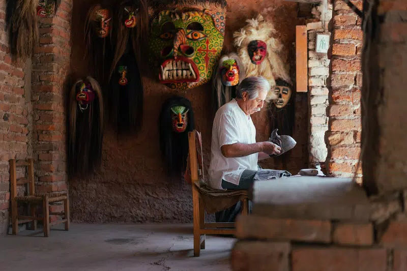 A man is doing craft work setting on a chair.