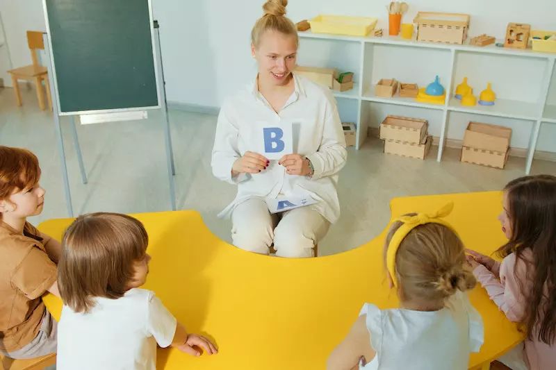 A Lady is teaching to the small kids in a classroom