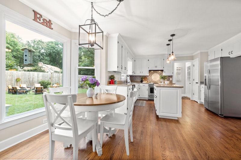 A kitchen with Fridge, dinning table and a open window.