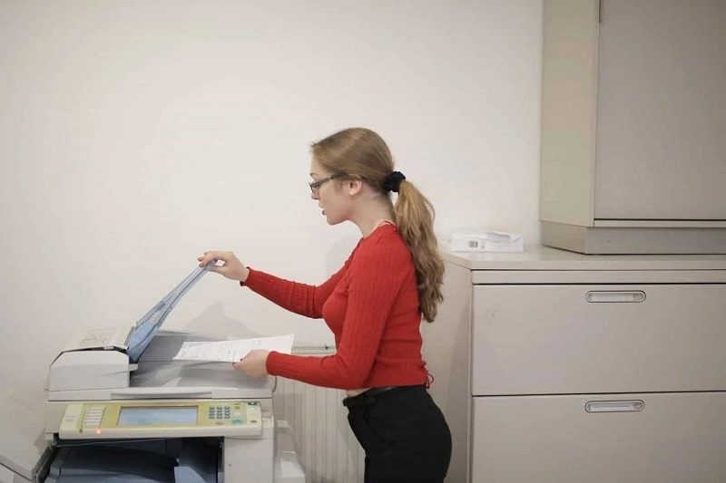 A lady is doing xerox work in the xerox machine