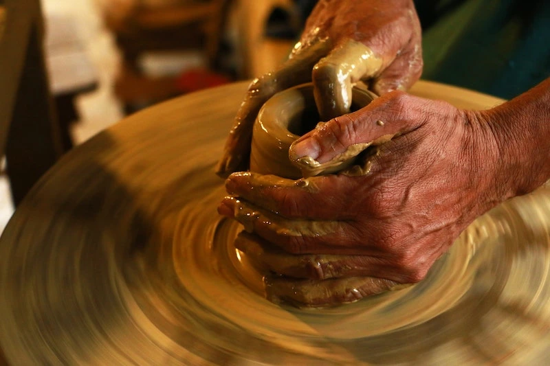 A Potter man is making pot with  a clay 