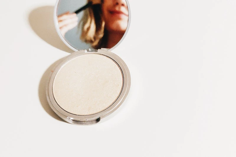 A lady is applying loose powder in her face 