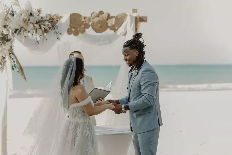 A bride and a groom holding hands of each other on the beach.