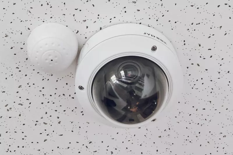A round white cctv camera placed on the wall 