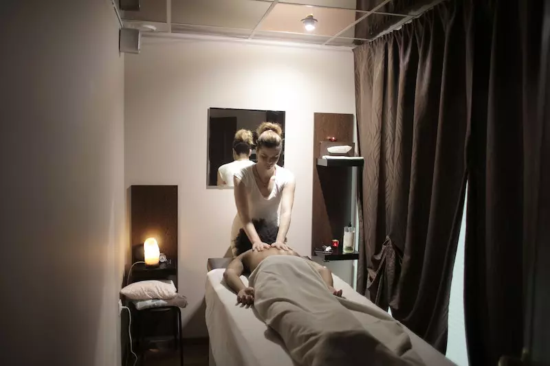 Professional masseuse doing massage for client in salon
