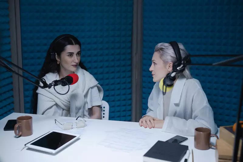 Two ladies are talking while wearing headphone
