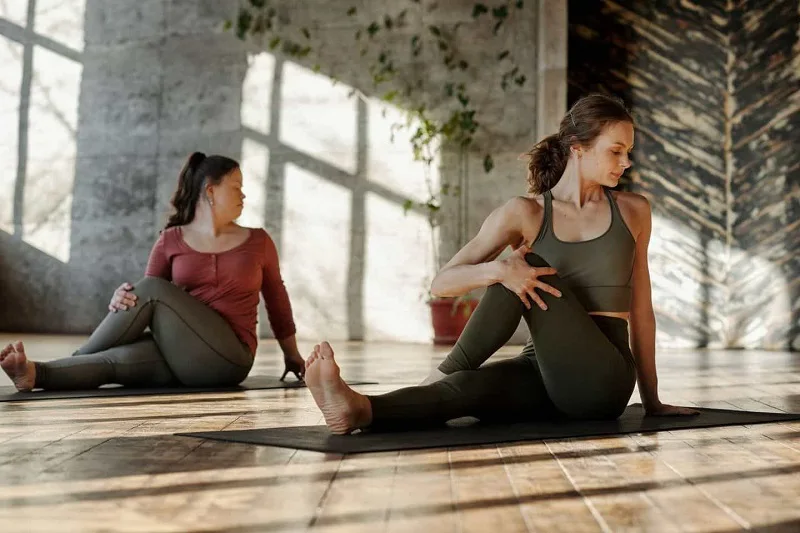 Two women performing yoga on a yoga mat.