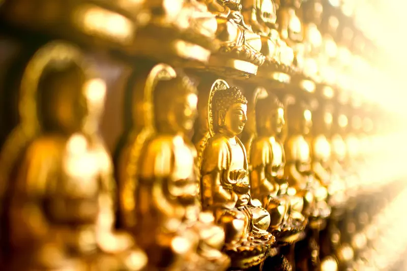 The golden statues of Gautam buddha carved on wall.