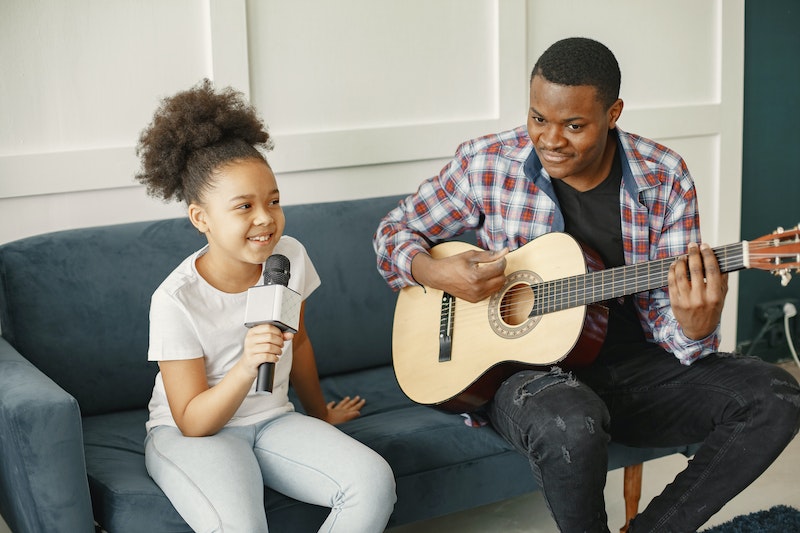 A girl is singing and a man is playing guitar