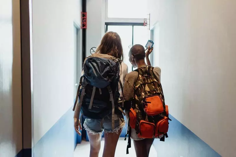 Two girls walking in the corridors with bags on his back.