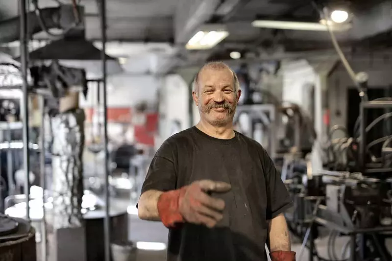 A man with black t-shirt and red gloves is laughing at the workplace.