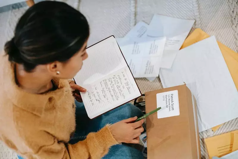 A women holding a book, reading something written on packed box.