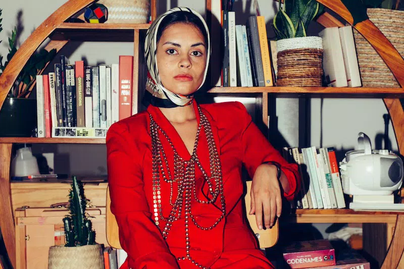 A lady wears  jewellery  and sit on the table 