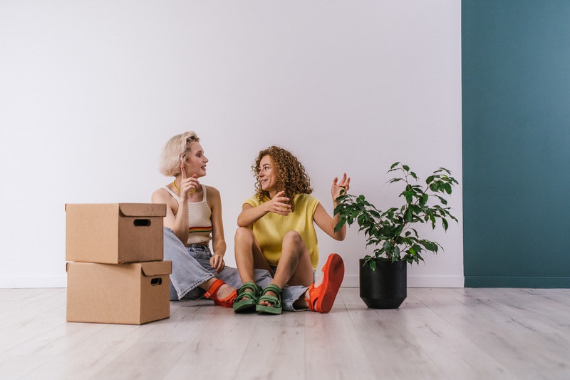 Two womens talking with a box on its side.