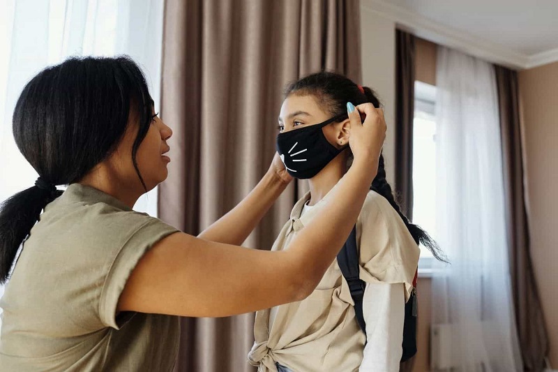A women giving mask to her child.