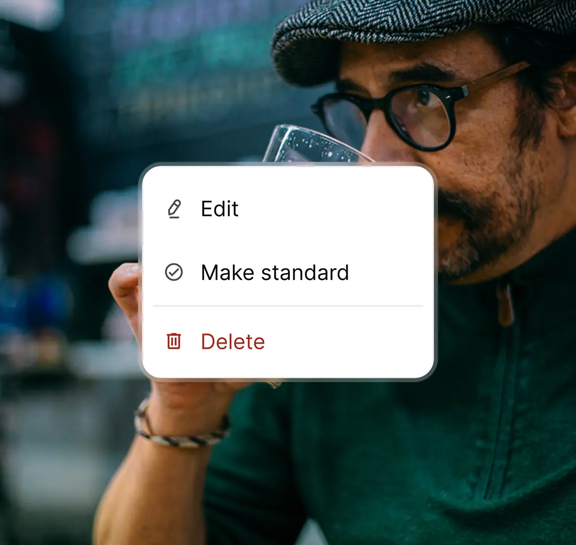 Man wearing glasses and a flat cap drinks from a glass with a menu overlay showing options to Edit, Make standard, and Delete.