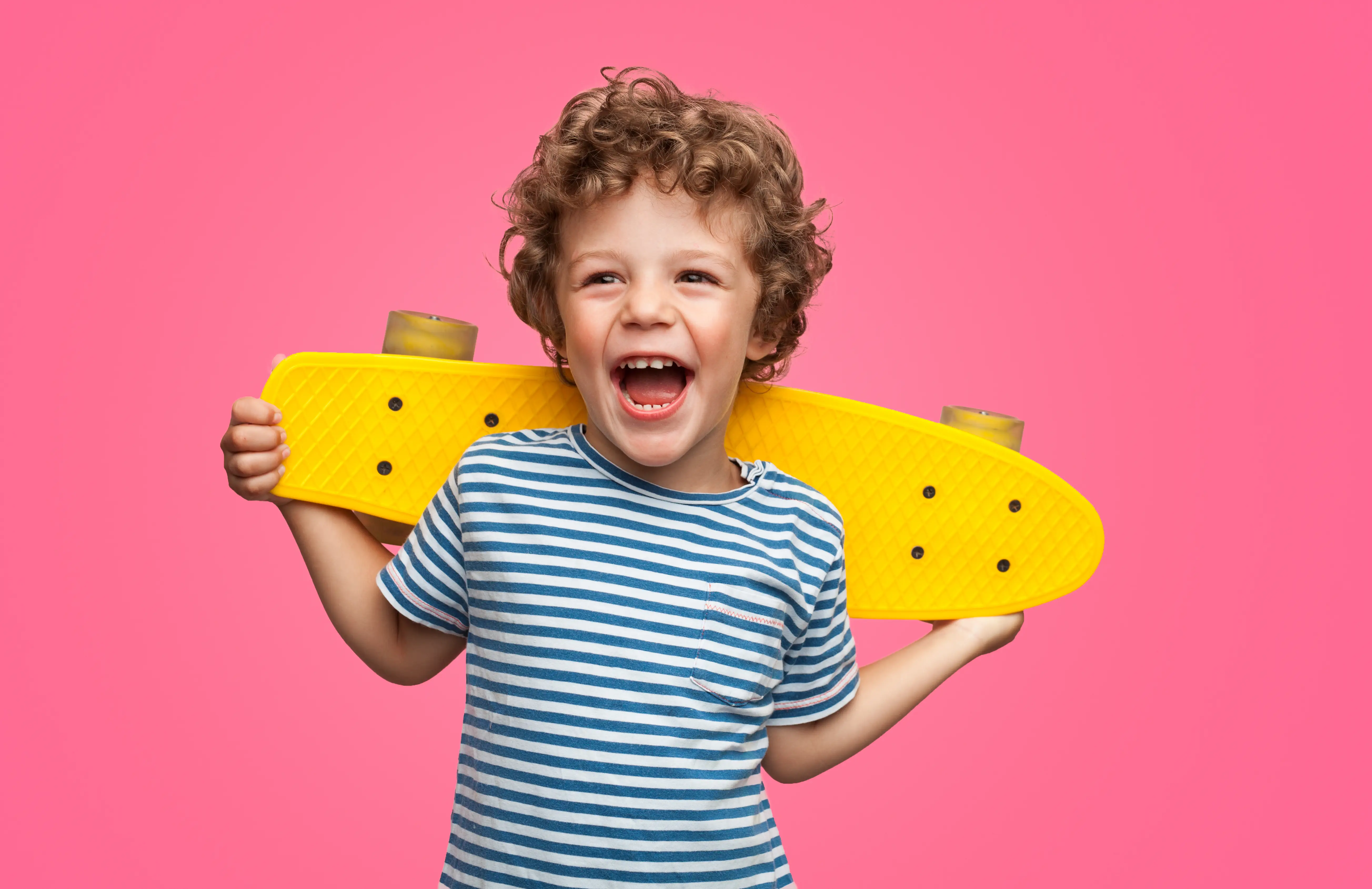 Child holding a skateboard and smiling