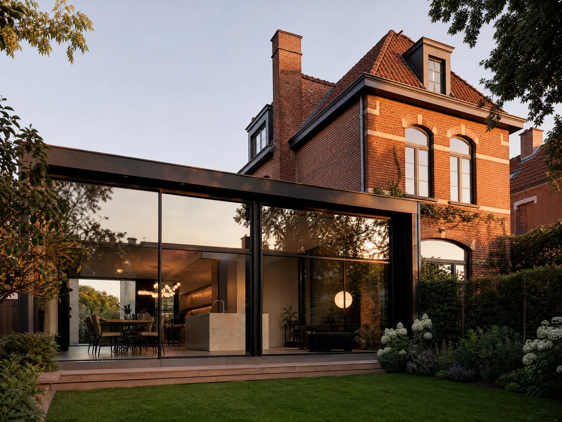 Maison en brique avec extension moderne en verre ouverte sur un jardin vert soigné.