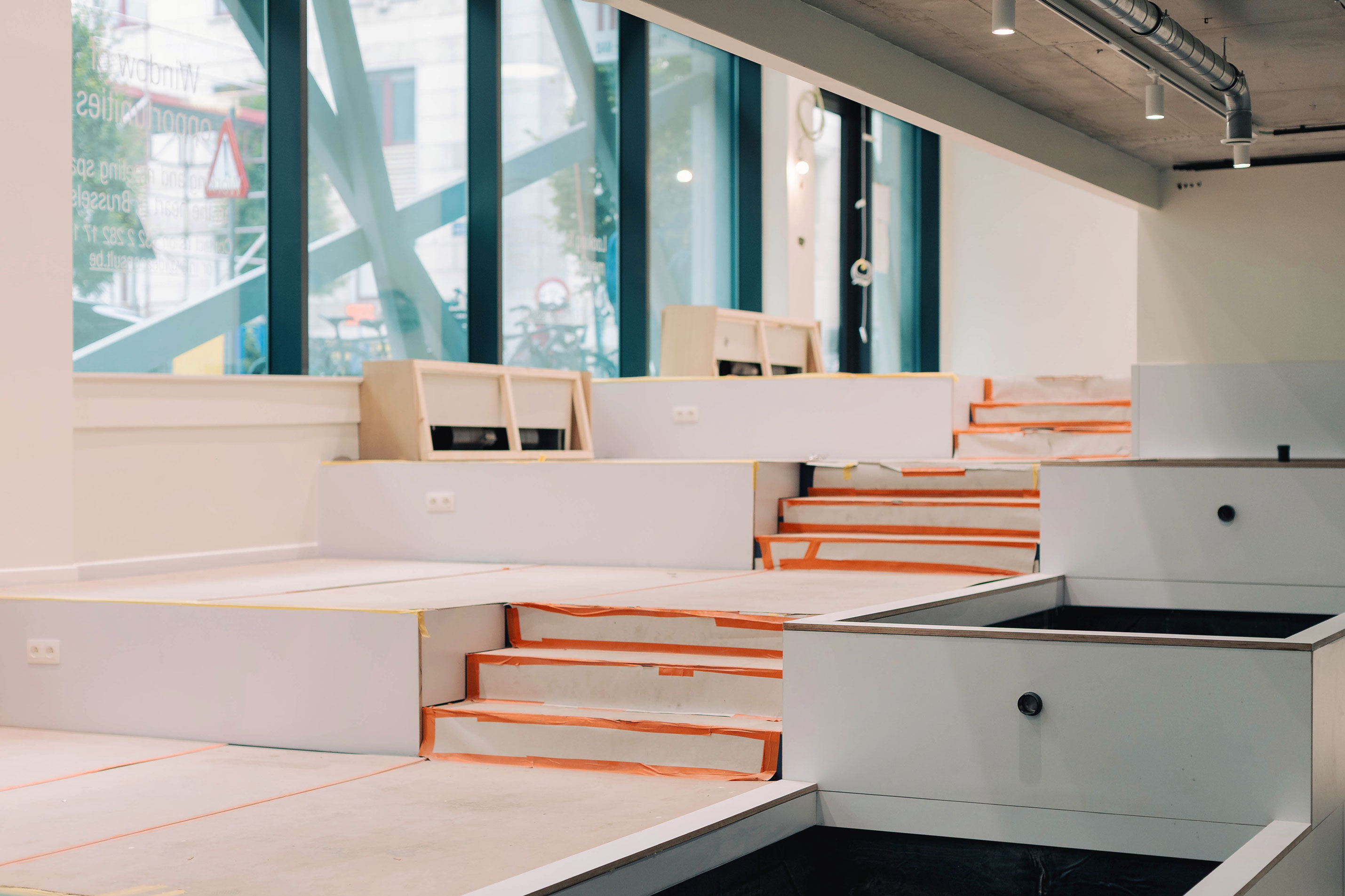Vue d'ensemble du chantier horeca avec les estrades blanches et les baies vitrées — EcoCasa-Construct