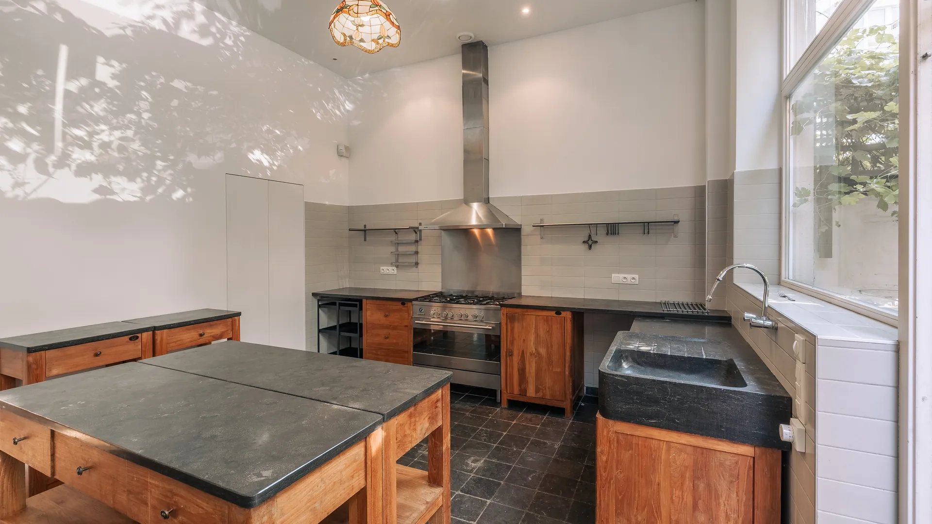 Cuisine : îlot en bois massif et plan en pierre bleue, grande hauteur sous plafond — maison rénovée à Saint-Gilles, Bruxelles