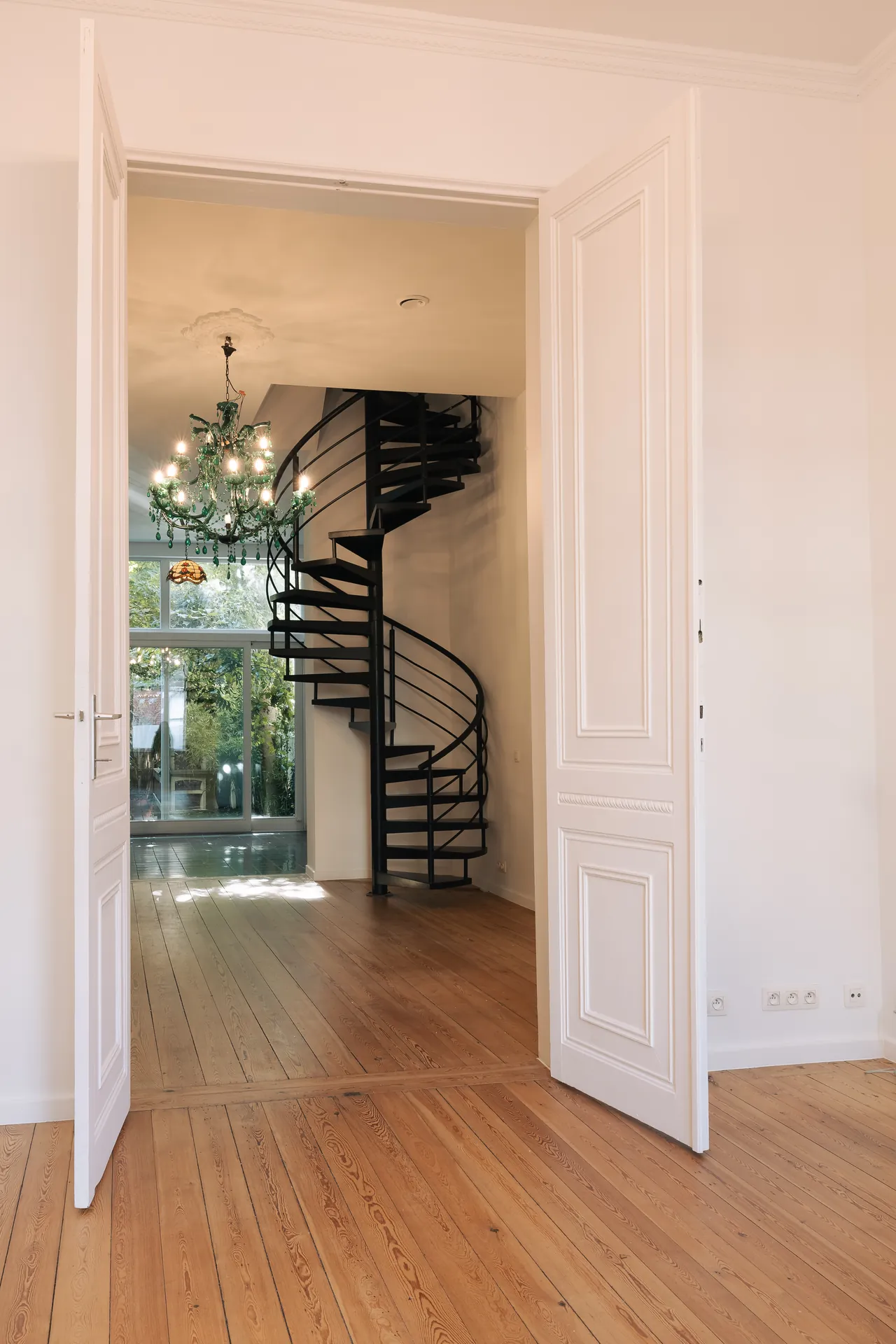 Double porte ouverte sur le séjour et l'escalier en colimaçon, parquet restauré — maison rénovée à Saint-Gilles, Bruxelles