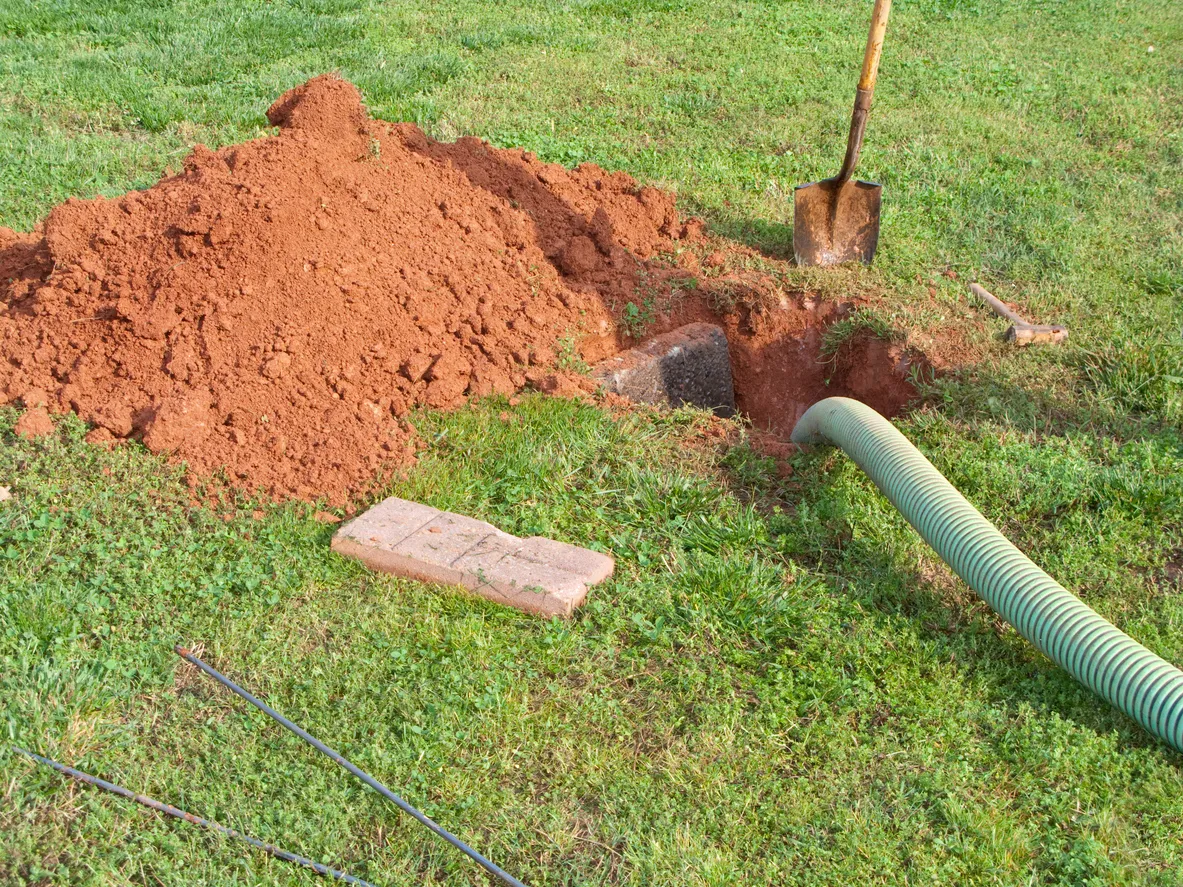 High pressure water jet cleaning a drain in an open manhole.