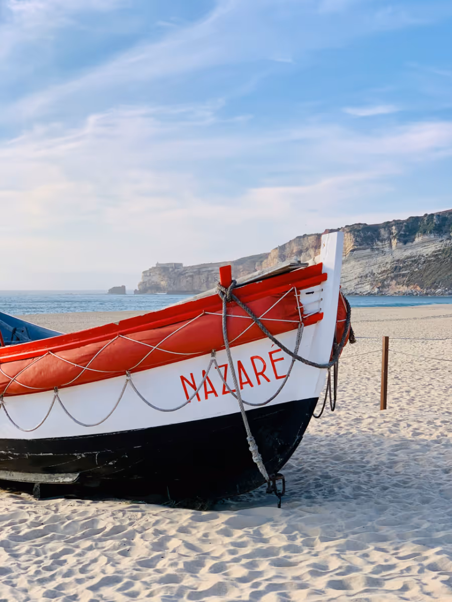 A red and white boat is on the beach.