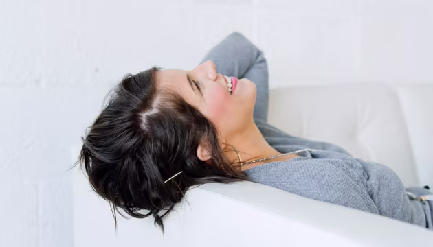 Woman smiling while relaxing on a white sofa