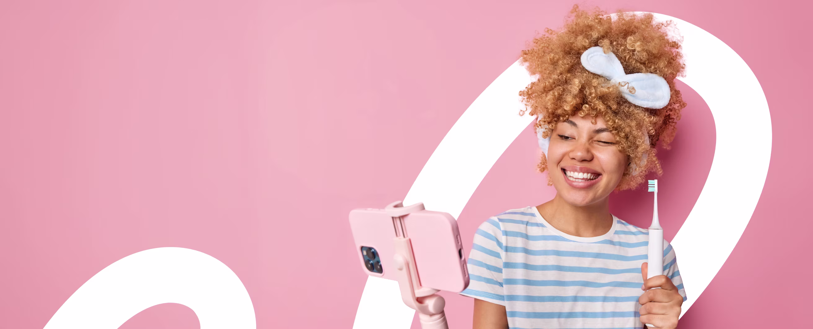 Smiling woman holding an electric toothbrush and taking a selfie