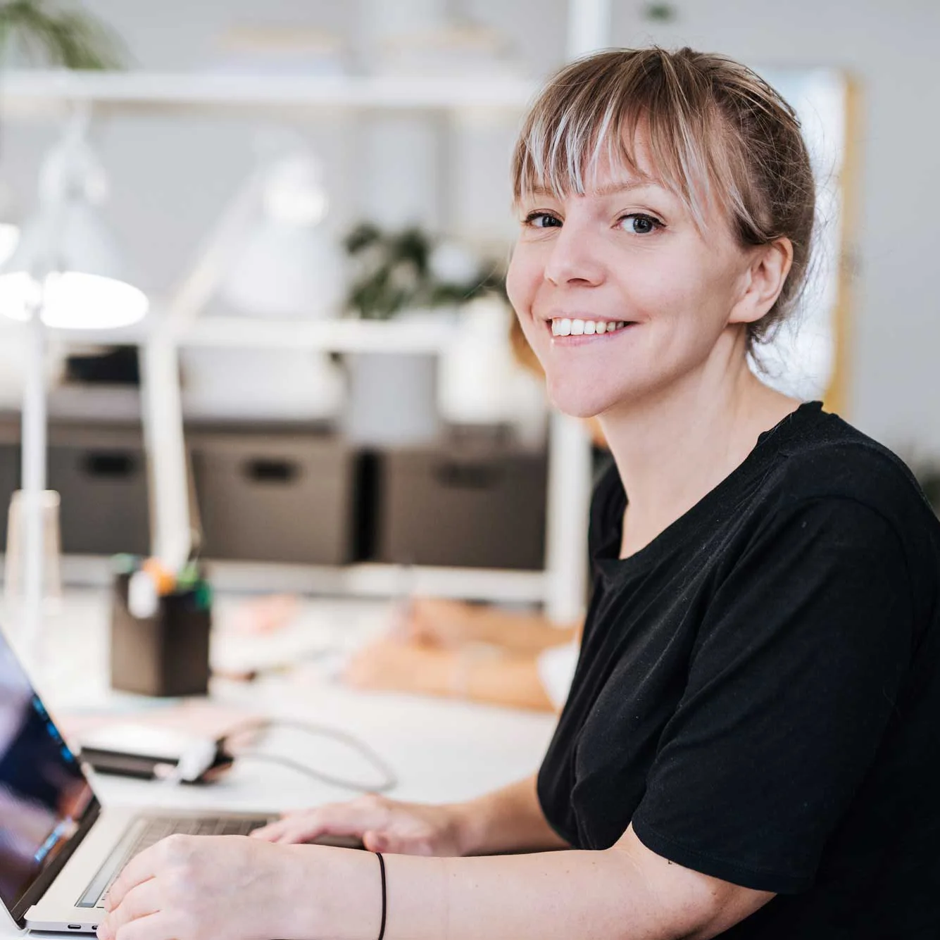 Kvinna som sitter vid ett skrivbord och ler