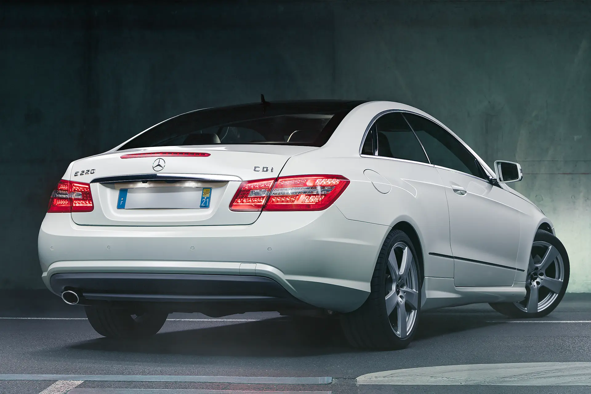 Mercedes Classe E coupé W212 blanche de 3/4 arriÚre avec une plaque d'immatriculation masquée
