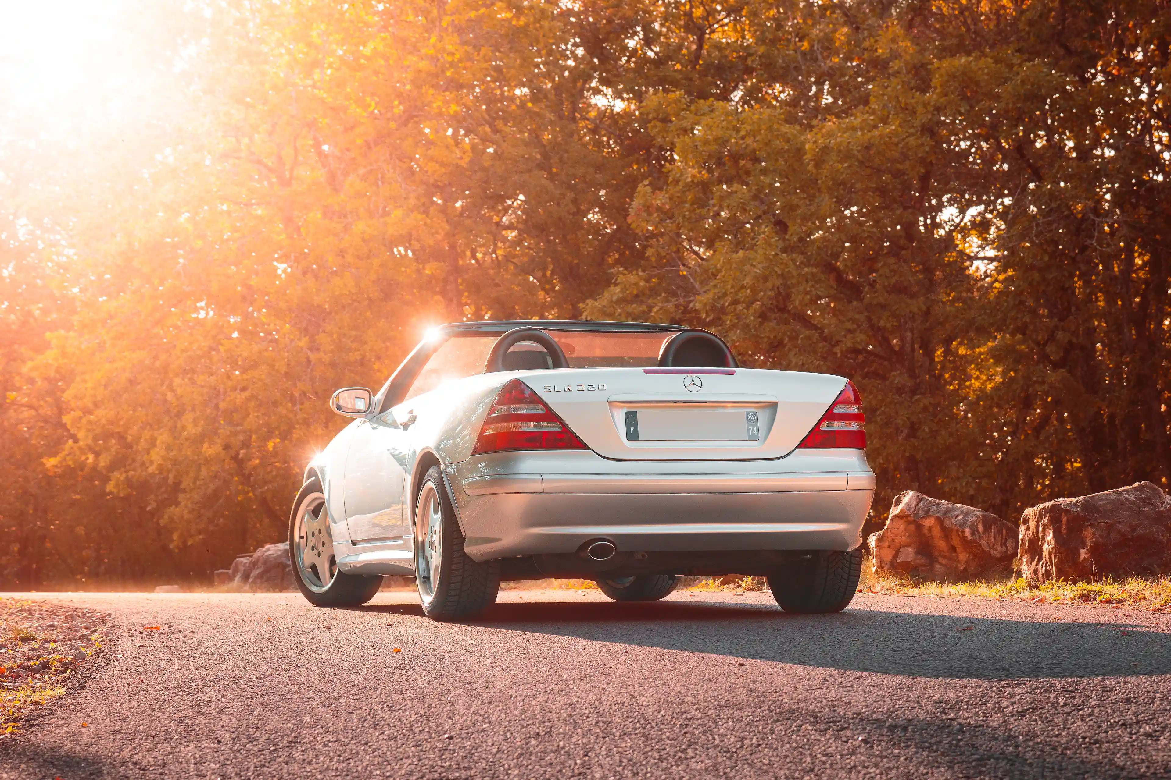 Mercedes SLK R170 grise de 3/4 arrière décapoté sous le soleil couchant en automne
