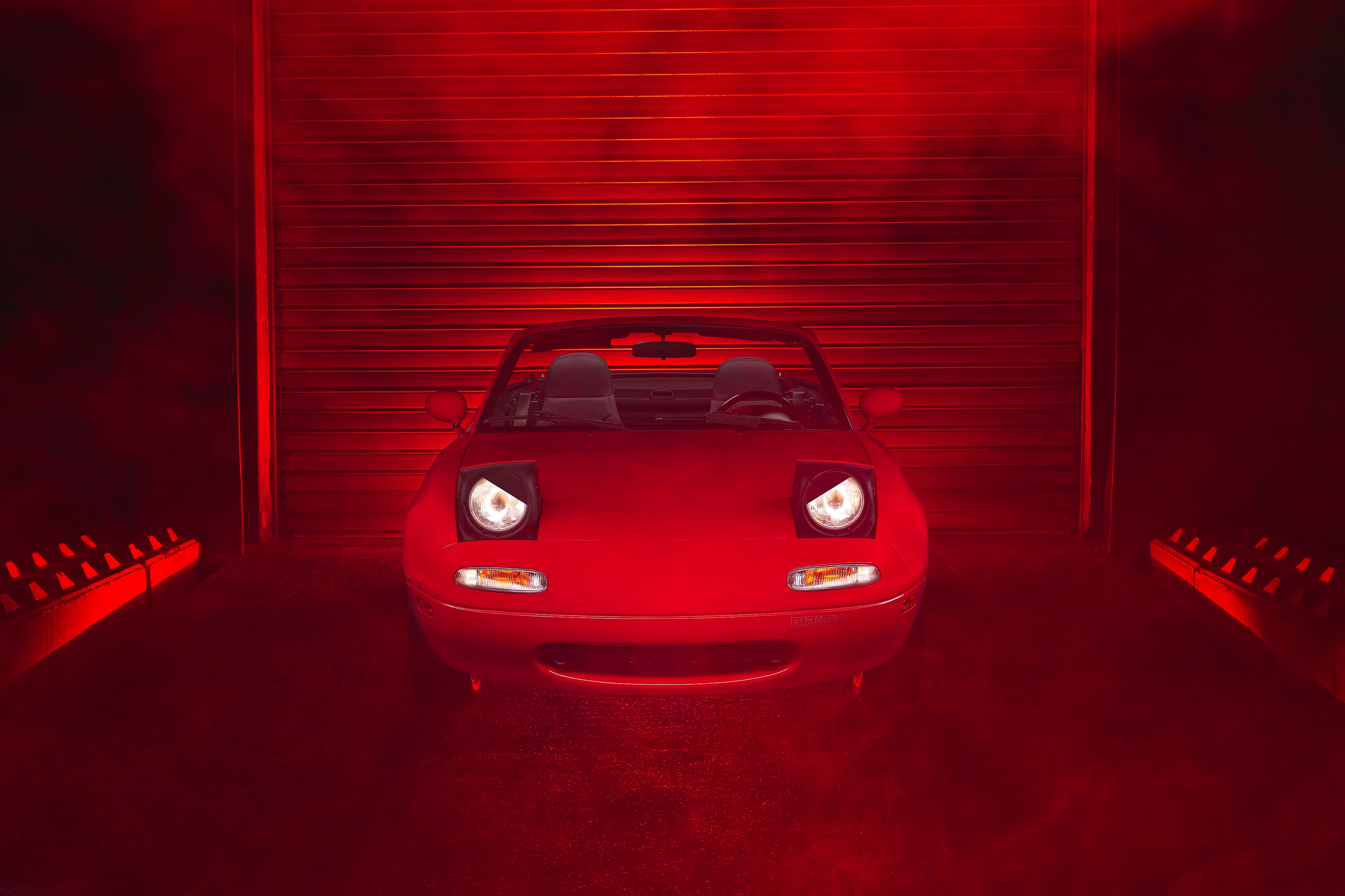 Mazda MX-5 NA rouge de face dans un décor industriel avec de la fumée en light painting