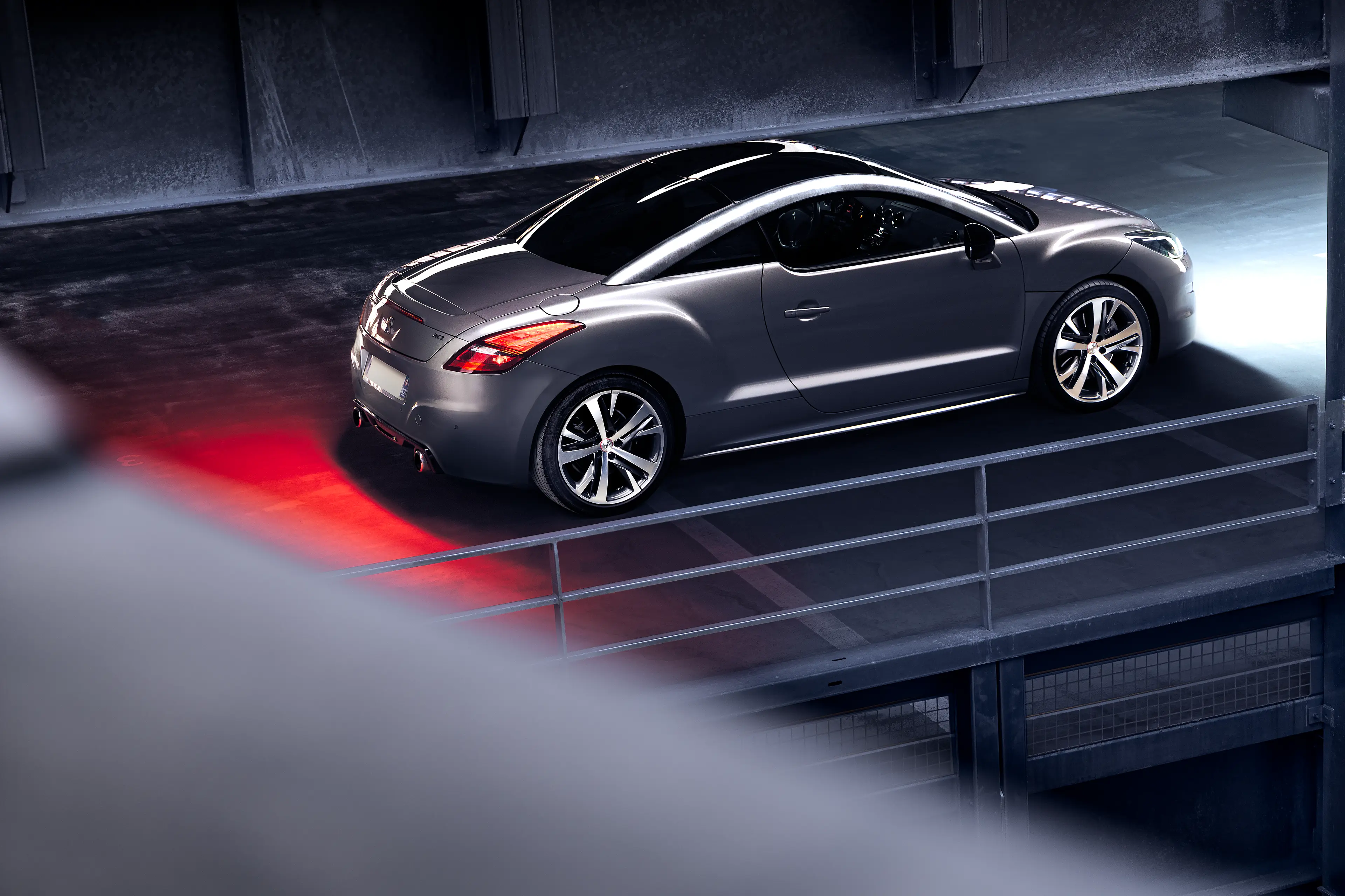 Peugeot RCZ grise de 3/4 arrière dans un parking sous-terrain en light painting