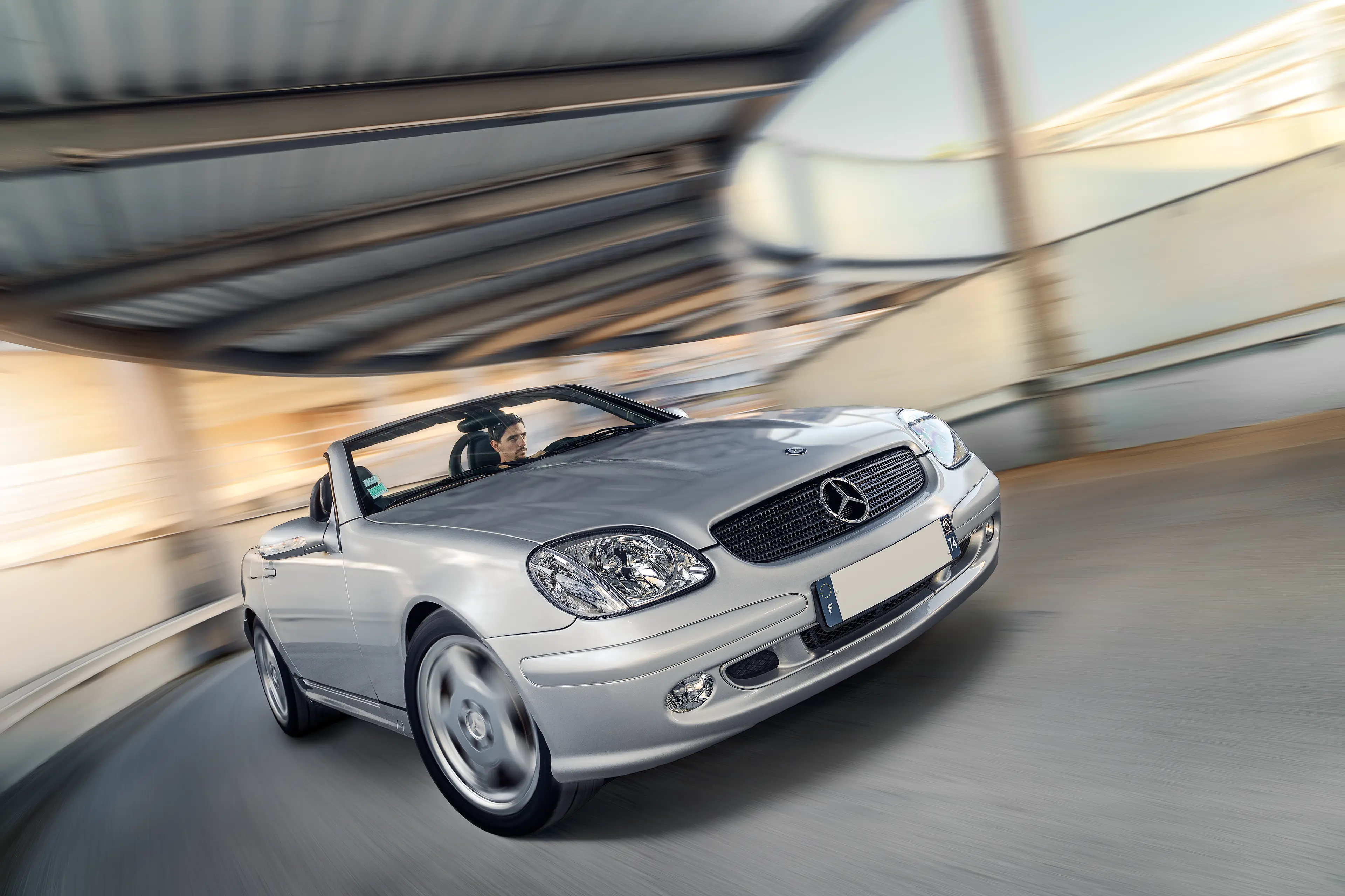 Mercedes SLK R170 grise de 3/4 avant roulant dans le colimaçon d'un parking