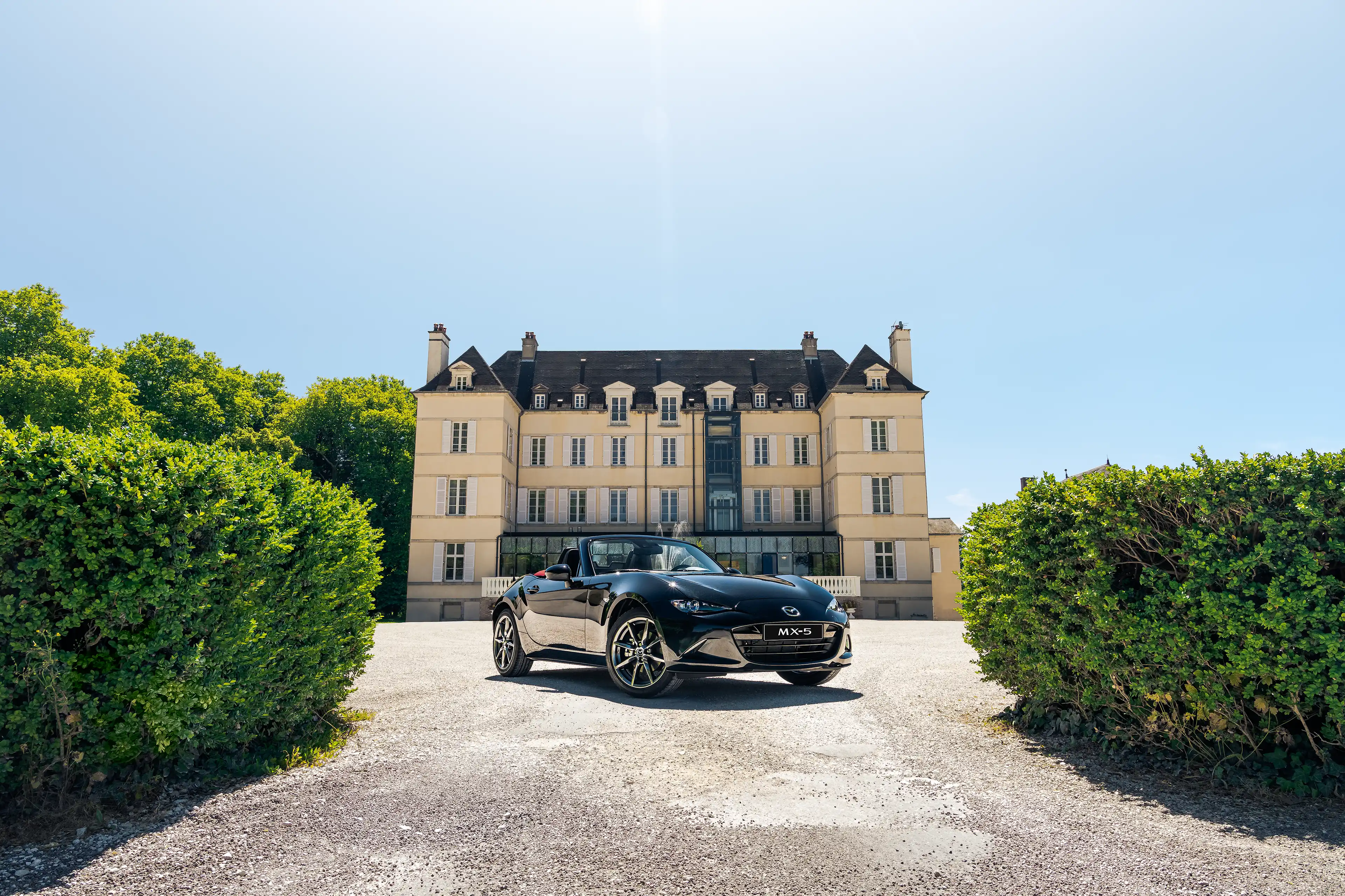 Mazda MX-5 ND noire de 3/4 avant devant le château de Saulon-la-Rue