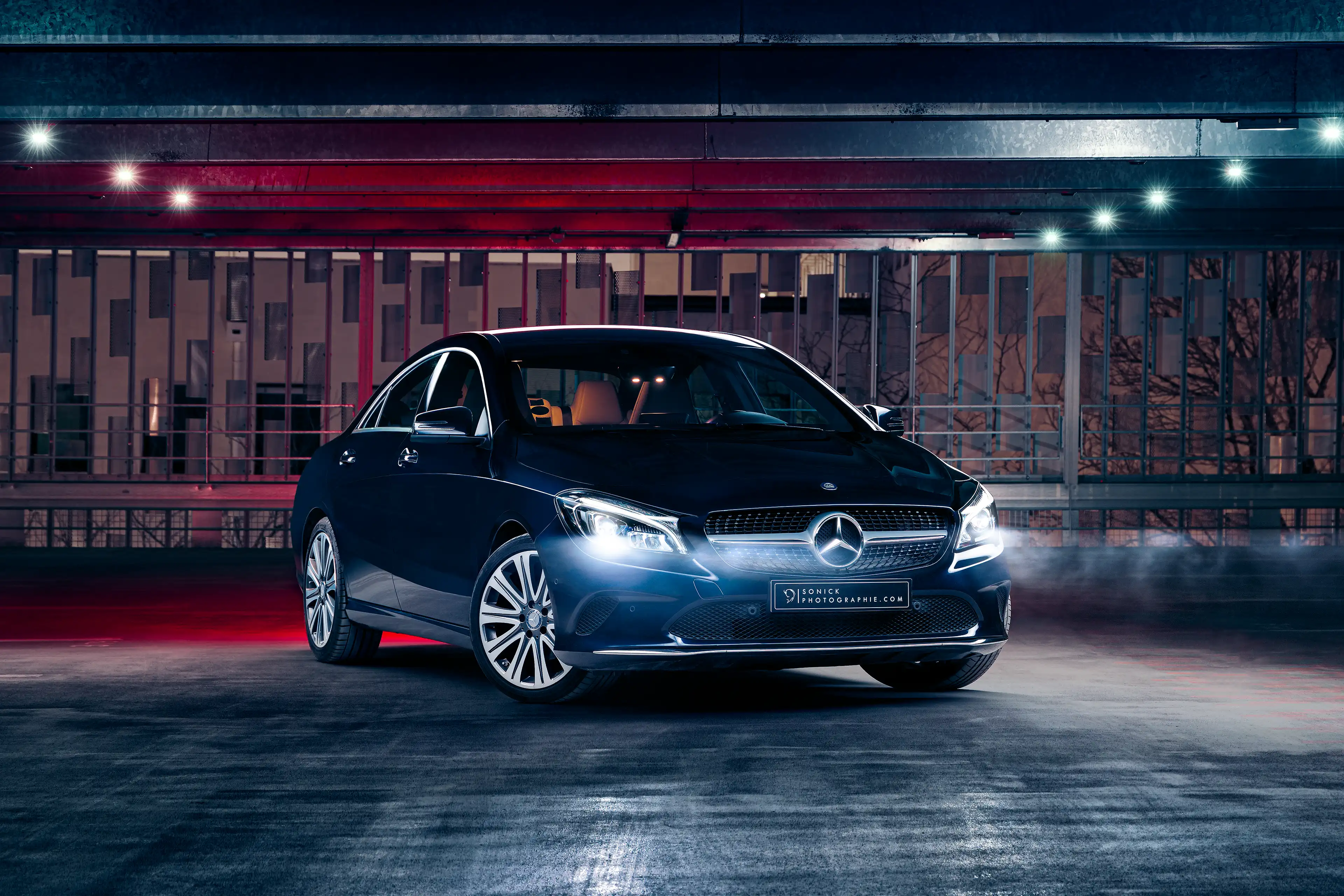 Mercedes CLA bleu foncée de 3/4 avant de nuit dans un parking en light painting