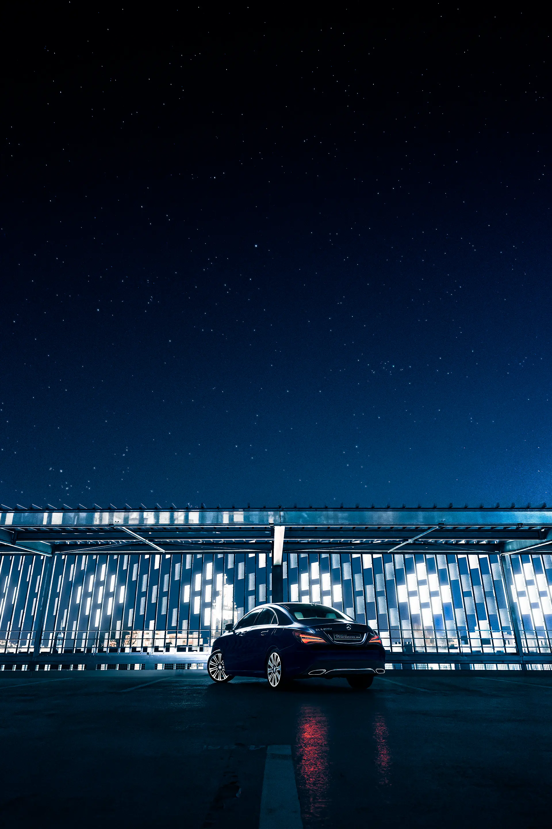 Mercedes CLA bleue foncée de 3/4 arriÚre de nuit sous un ciel étoilé en light painting