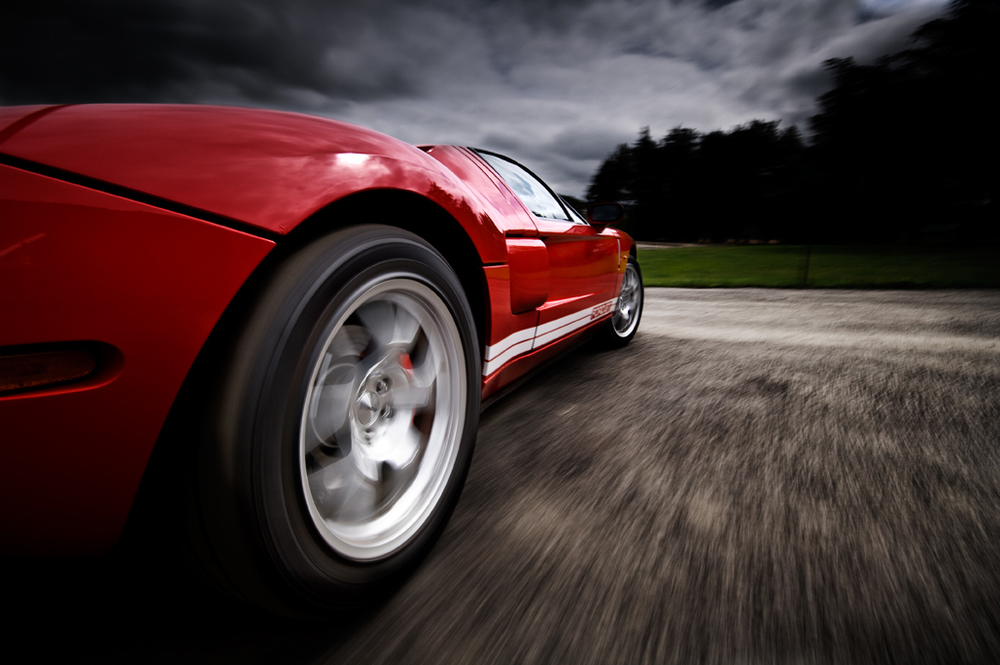 Rigshot d'une Ford GT rouge en mouvement tournant à droite, prise grâce à un rig, gros plan sur la roue arrière